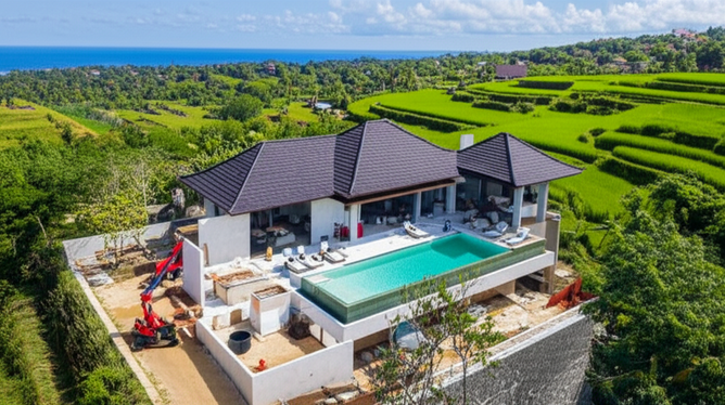 Aerial view of a luxury villa under construction in Bali, showcasing the beauty of its surroundings and the construction process.