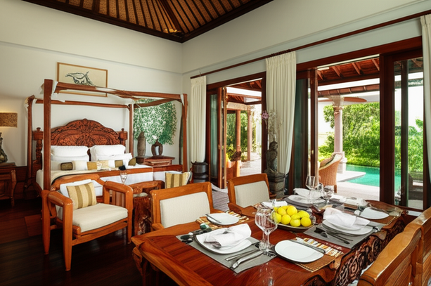 Luxurious Balinese villa interior with custom wooden furniture, artwork, and an outdoor veranda.