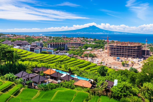 Panoramic view of Bali's construction boom, showcasing modern buildings alongside traditional Balinese architecture and the island's natural beauty.