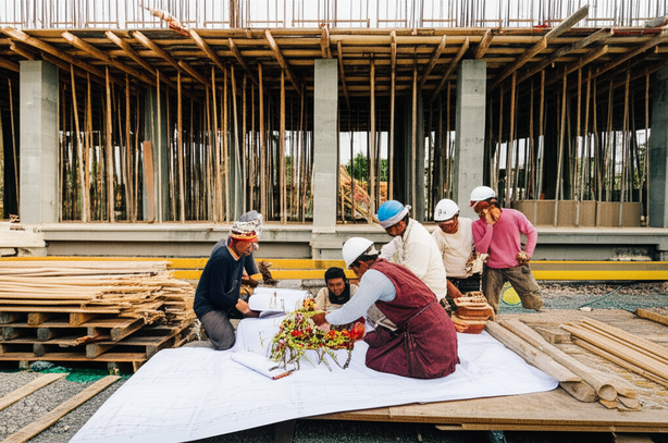 A construction site in Bali, showcasing a harmonious blend of Balinese culture and modern construction, with workers collaborating on a building project.