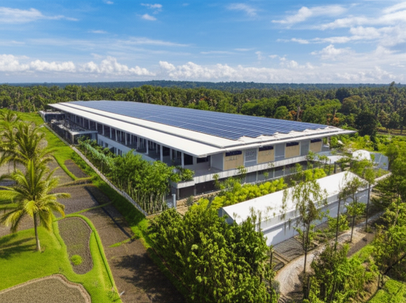 A sustainable industrial facility in Bali, showcasing green building techniques like solar panels and natural ventilation, harmonizing with the tropical landscape.