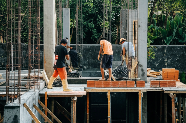 Villa construction in Bali, showing the structural framework being built with reinforced concrete and initial wall construction.