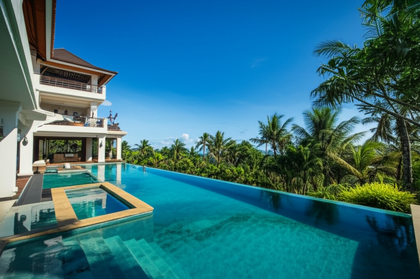 A luxurious Bali villa with a perfectly maintained pool and tropical gardens, showcasing the benefits of professional property management.
